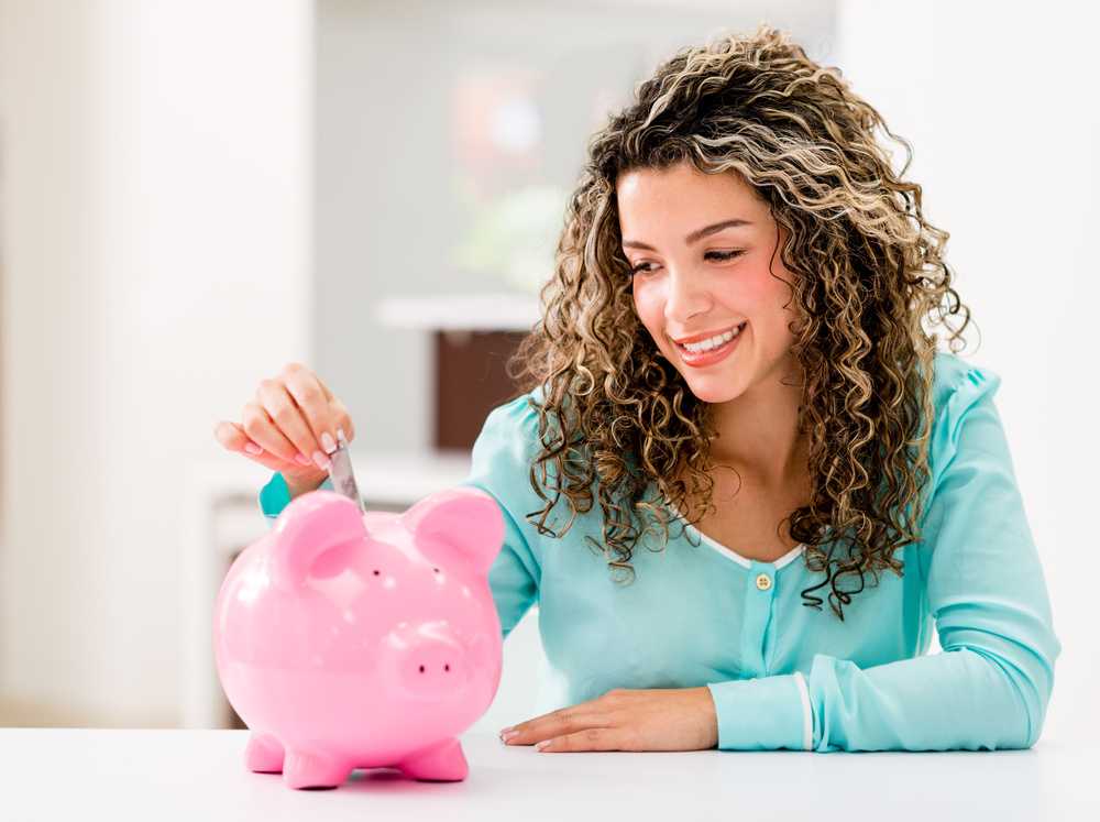Happy woman saving money in a piggybank Happy woman saving money in a piggybank